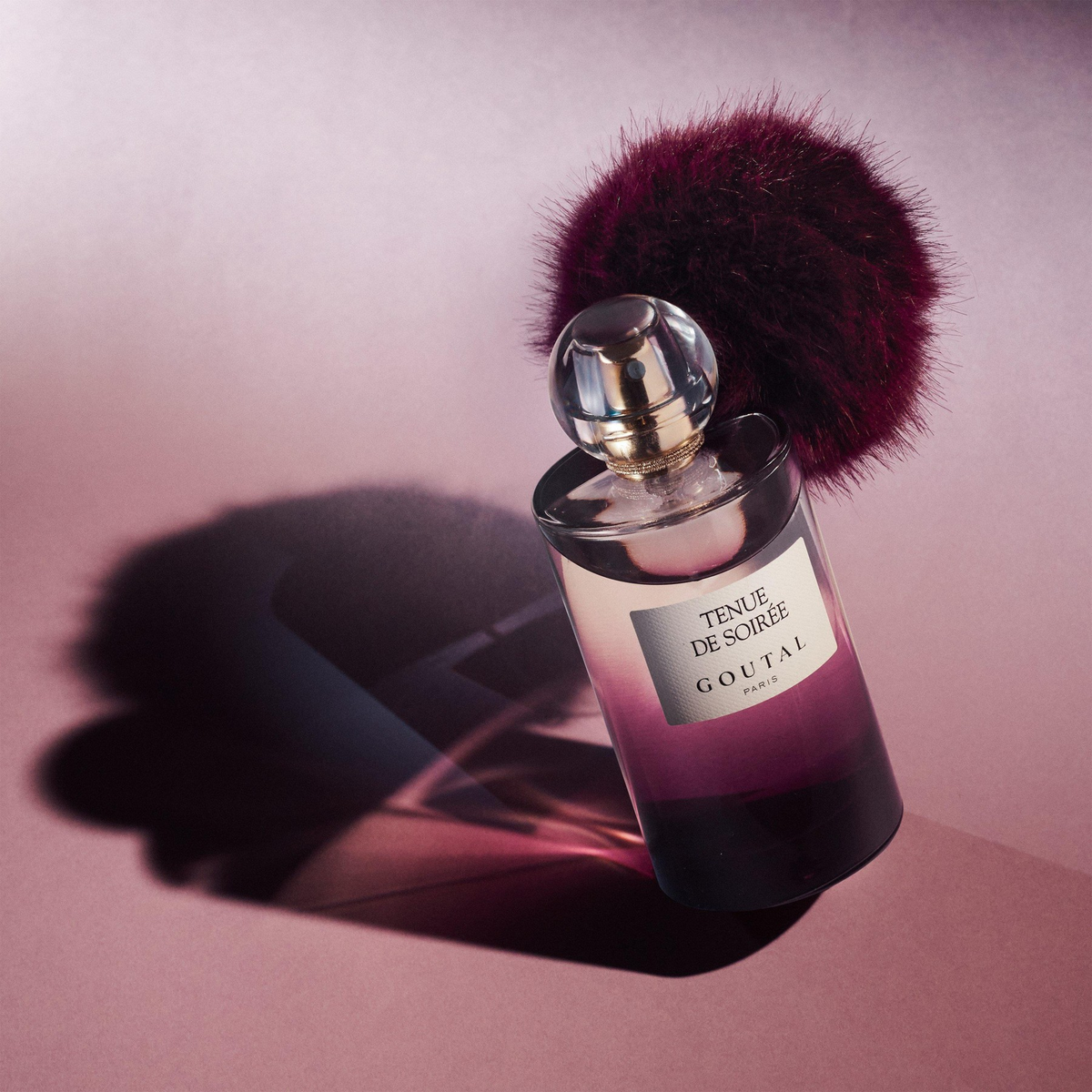 Goutal Tenue de Soirée parfum with burgundy pompom on pink background