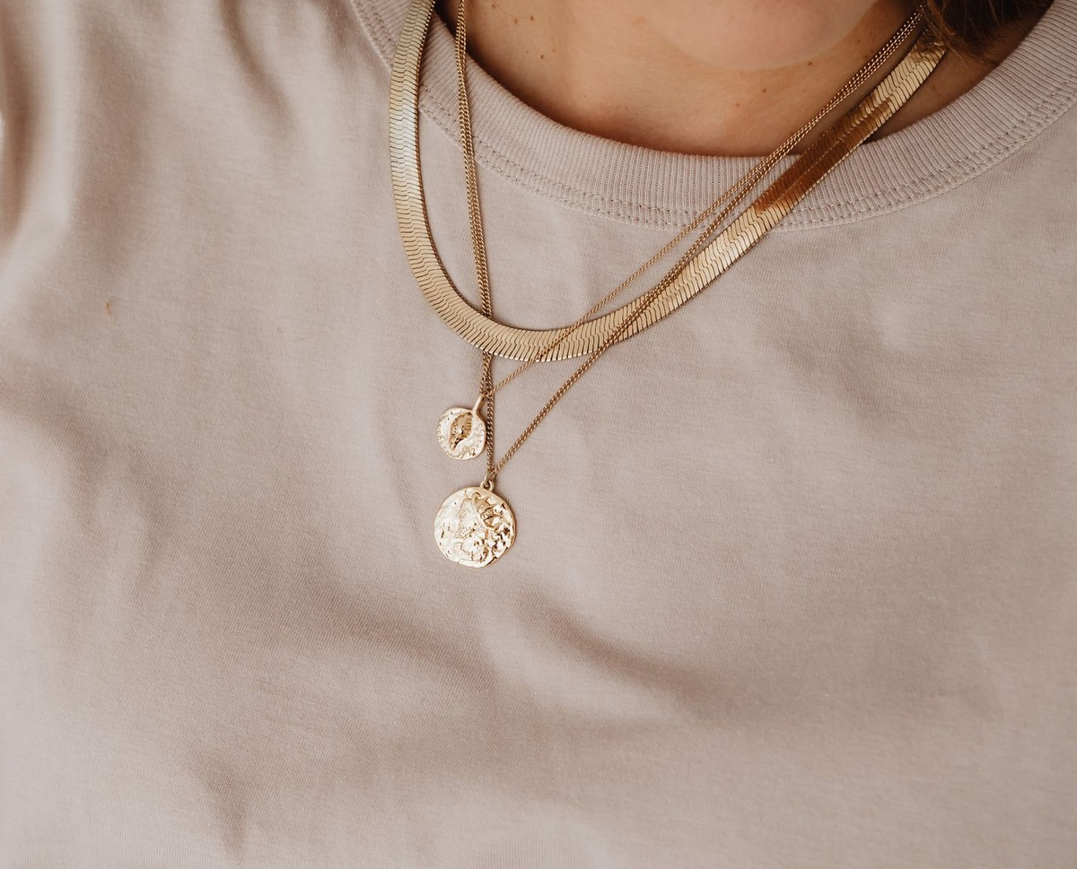 Een delicate gouden hanger op crème satijn